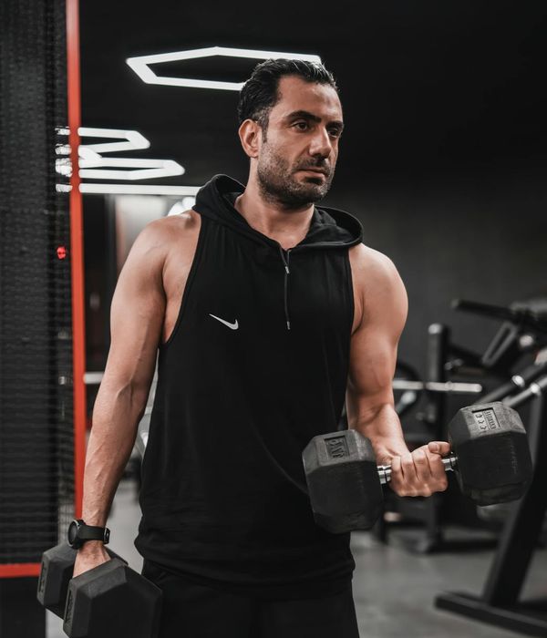 Athletic man performing strength exercises in a modern dark gym